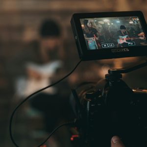 A cinematic close-up of filming a rock band performance with focus on camera screen.