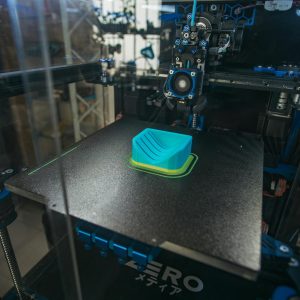 Close-up of a 3D printer creating a plastic object in an industrial setting.