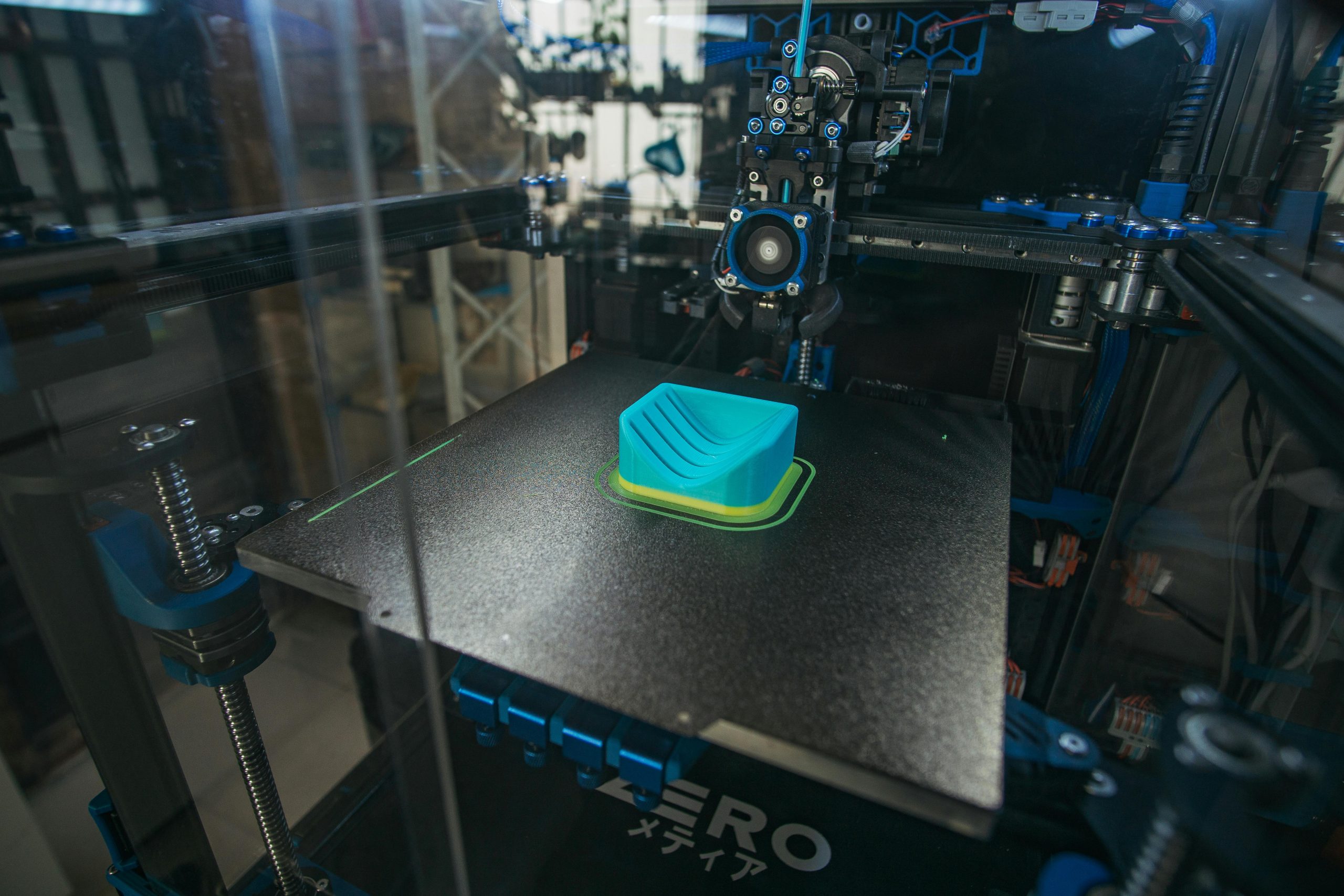 Close-up of a 3D printer creating a plastic object in an industrial setting.
