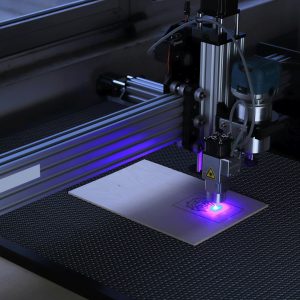 Close-up of a CNC laser engraving machine processing a wooden piece.